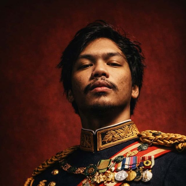 Portrait of Robby Roda, developer of Nyvo, in a dark ceremonial uniform against a deep red background